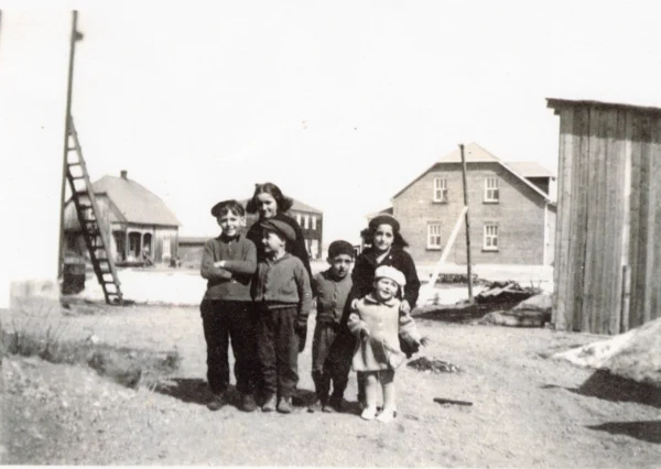 Jacynthe Gilbert — 1951 — famille — Tags: maison, famille — Photo prise derrière l\'épicerie de Lorenzo Lemieux, à gauche la boucherie Léonce Gagné, maison noire d\'Edgar Bouchard le cantonnier, en face Raymond Lemieux (site sur lequel était la chapelle), hangar de l\'épicerie, 6 des enfants d\'Armand Gilbert, 1951
