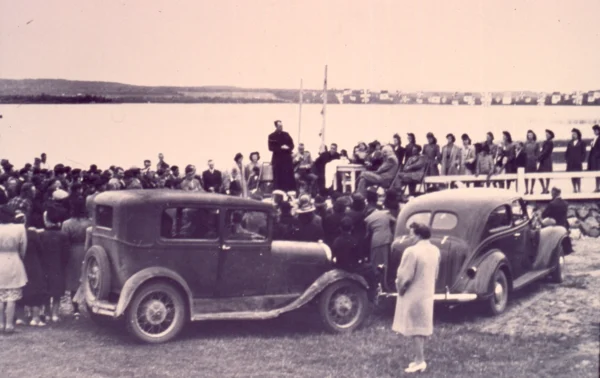 inconnu — 1946 — lac — Tags: église, pont, lac, voiture — En 1946, le curé Léonidas Dufour (1896-1983) bénit le pont en présence du député Antonio Talbot (1900-1980). À l\'époque, il est courant au Québec de bénir les infrastructures publiques. Le geste symbolise la concrétisation du projet et la demande de protection divine pour garantir la sécurité, la prospérité et la durabilité de l\'infrastructure.